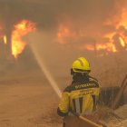 Un bombero rocía con agua neumáticos y barriles en llamas cerca de Ávila, España