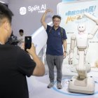 Un visitante y un robot humanoide hacen gestos de corazón mientras posan para fotos durante la Conferencia Mundial de IA 2026, en Shanghái.
