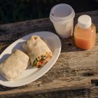 Burritos con café y zumo en una mesa rústica de madera, bajo la cálida luz del sol. California, EEUU