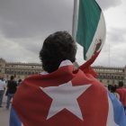 Una persona con una bandera cubana frente a la bandera de México (Archivo)