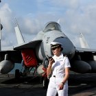 Una efectivo de la Armada estadounidense se encuentra junto a un avión en la cubierta del portaaviones USS George Washington.