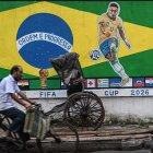 Un ciclista pasa junto a un grafiti con las imágenes del futbolista brasileño Neymar