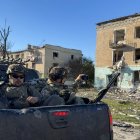 Soldados de Ucrania pasan en una camioneta junto a los edificios dañados