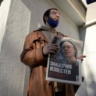 Un hombre sostiene un periódico con la foto de la periodista de investigación Anna Politkovskaya