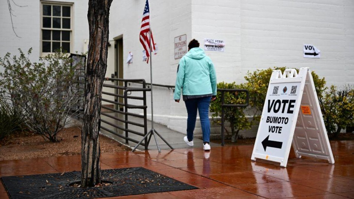 Una persona frente a un cartel colocado afuera de un centro de votación el día de las elecciones primarias presidenciales de Nevada 2024