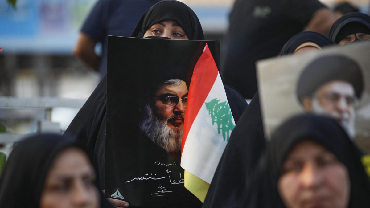 Una mujer sujeta un retrato del líder de Hezbolá Nasrallá junto a una bandera libanesa