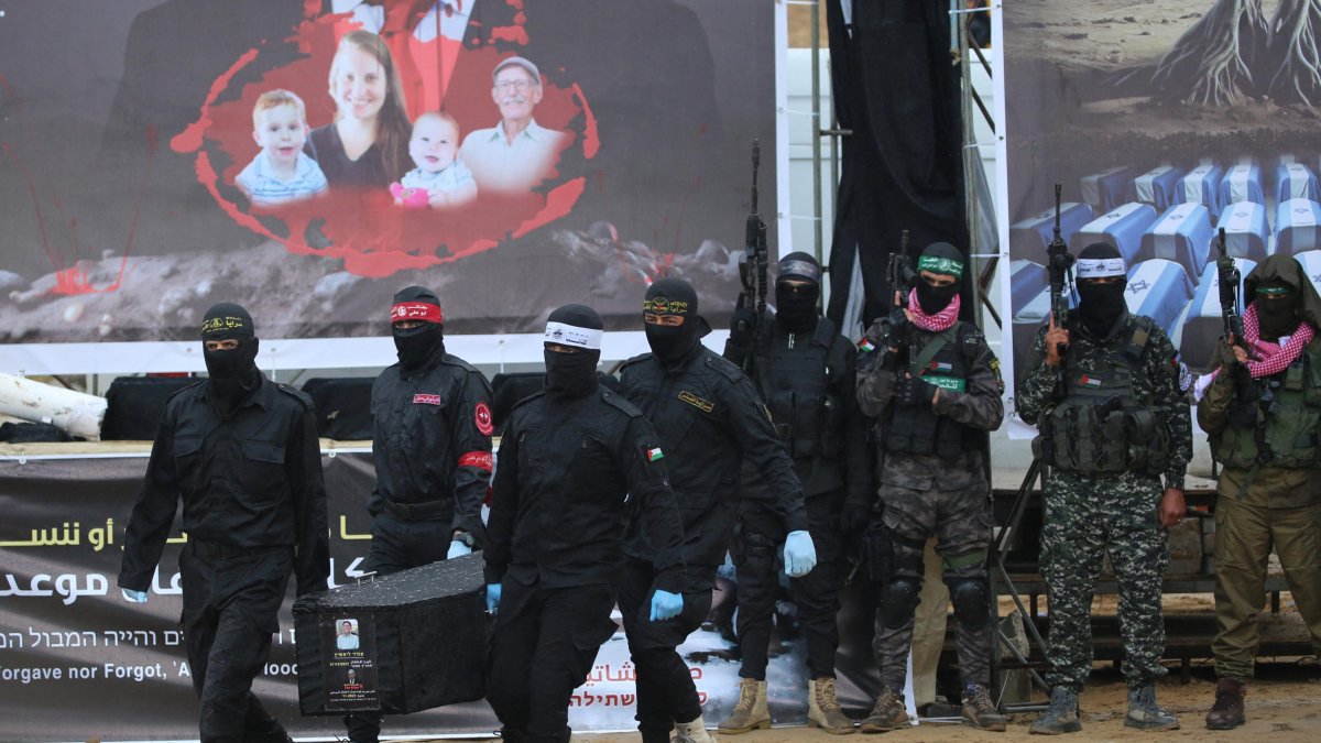 Palestinian terrorists carry one of the coffins as they hand over the bodies of four Israeli hostages