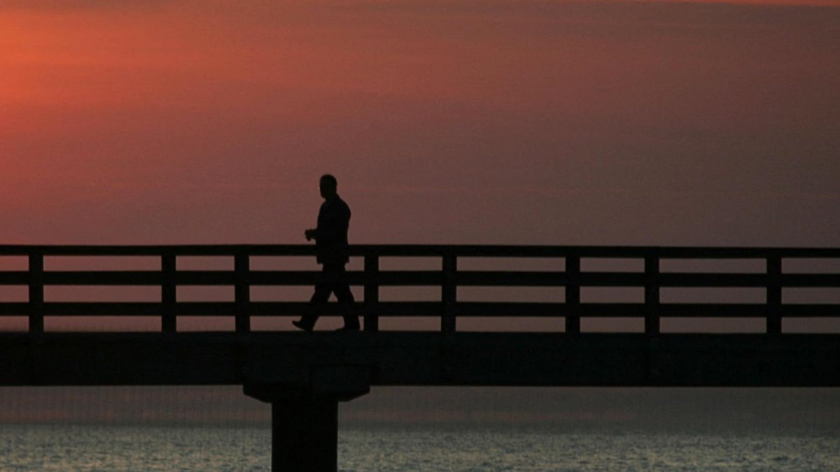 Un hombre solitario camina por un muelle