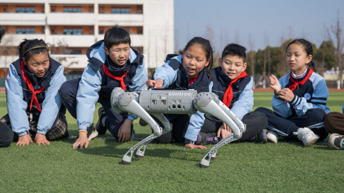 Students interact with a robot dog during a class break at Xinyi Elementary School.