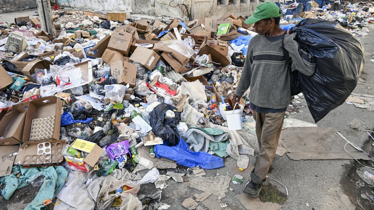 A man walks down a Havana street that has been turned into a garbage dump.