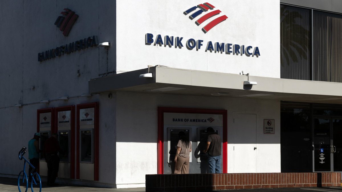 People use ATMs at a Bank of America branch.