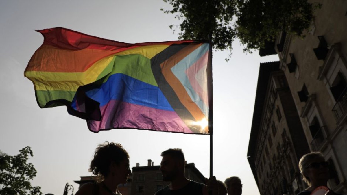 Bandera trans sobre figuras en negro.