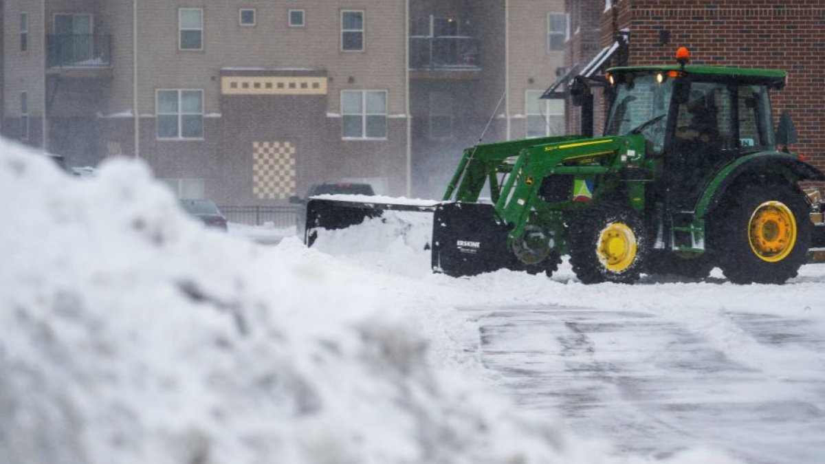 Un tractor quita la nieve de un estacionamiento en Ankeny, Iowa, el 12 de enero de 2024 | Jim WATSON / AFP
