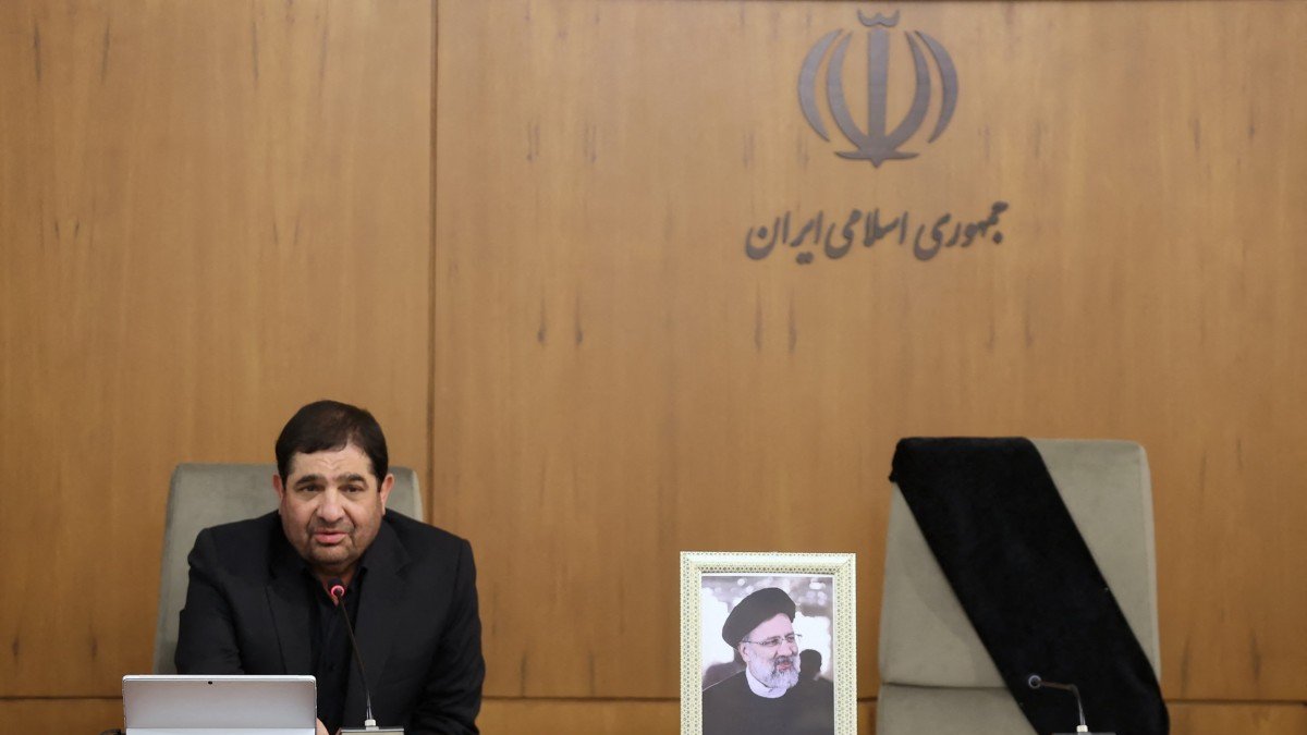 A handout picture released by the Iranian presidency shows Iran's First Vice President Mohammad Mokhber, with the seat of the late president Ebrahim Raisi (portrait) next to him empty, addressing the country's cabinet in Tehran on May 20, 2024. - After Iranian President Ebrahim Raisi and Foreign Minister Hossein Amir-Abdollahian were confirmed dead on May 20 when search and rescue teams found their crashed helicopter in a fog-shrouded western  Iranian mountain region, the Islamic republic's supreme leader, Ayatollah Ali Khamenei, declared five days of mourning and assigned Mokhber, 68, to assume interim duties ahead of elections within 50 days. (Photo by Iranian Presidency / AFP) / === RESTRICTED TO EDITORIAL USE - MANDATORY CREDIT 