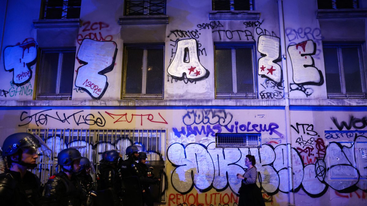 A woman walks in front of riot police in Paris on election night.