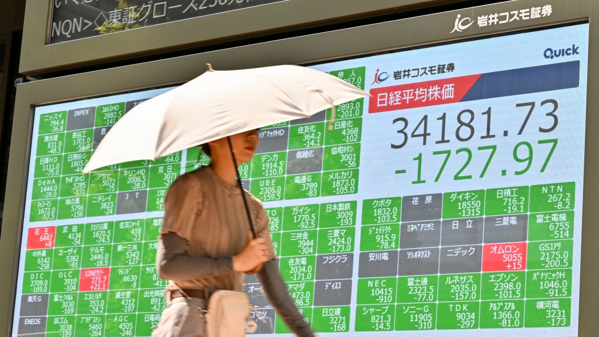Un peatón pasa junto a un tablón que muestra los números de la mañana en la Bolsa de Tokio.