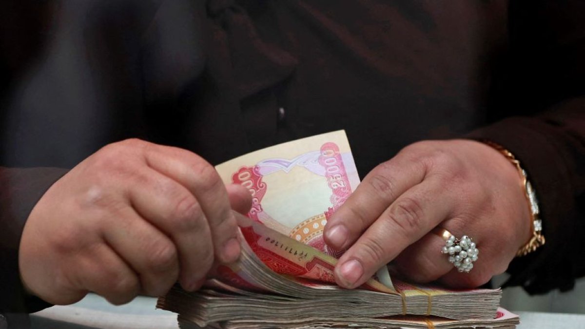 Una persona contando dinares iraquíes