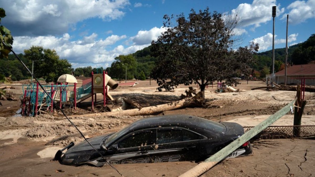 Un coche de la policía local se ve medio envuelto en barro, en una zona inundada del lago Lure, Carolina del Norte, tras el paso del huracán Helene