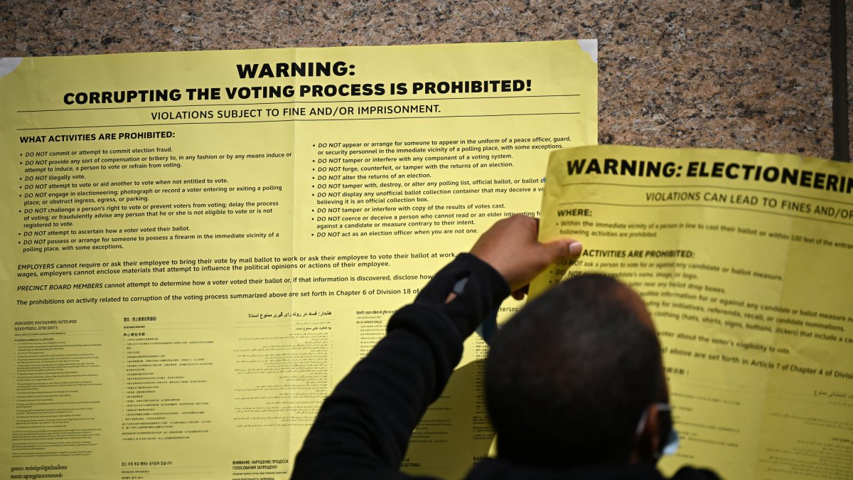 Un trabajador pega carteles de advertencia contra el fraude electoral