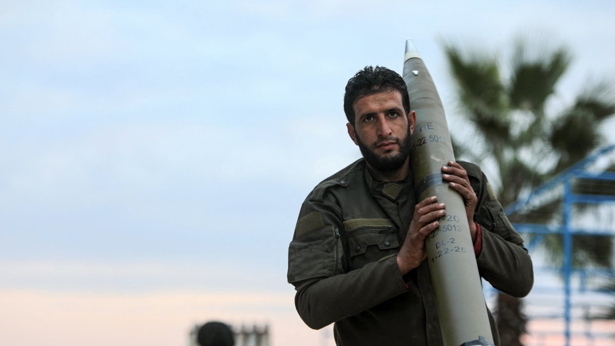 Un rebelde islamista carga con munición de artillería a las afueras de Hama