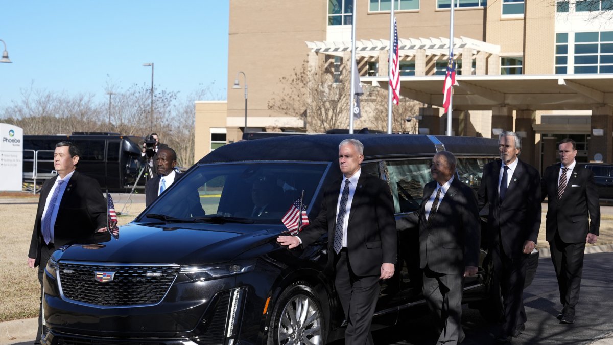 Antiguos y actuales miembros del Servicio Secreto escoltan el coche fúnebre de Jimmy Carter