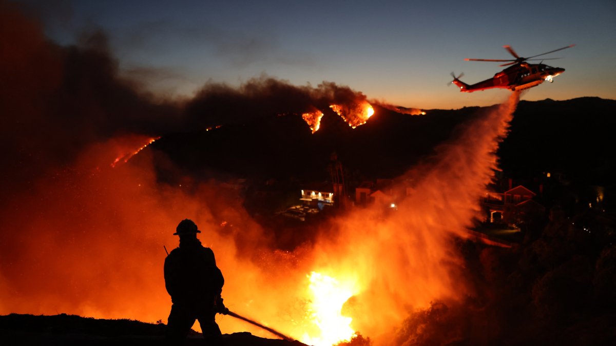 Firefighters respond to destroyed homes as helicopter drops water on Palisades blaze