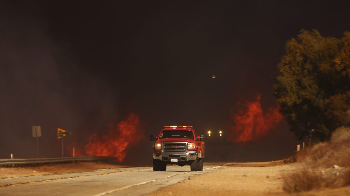 A fire truck drives past the Hughes Fire.