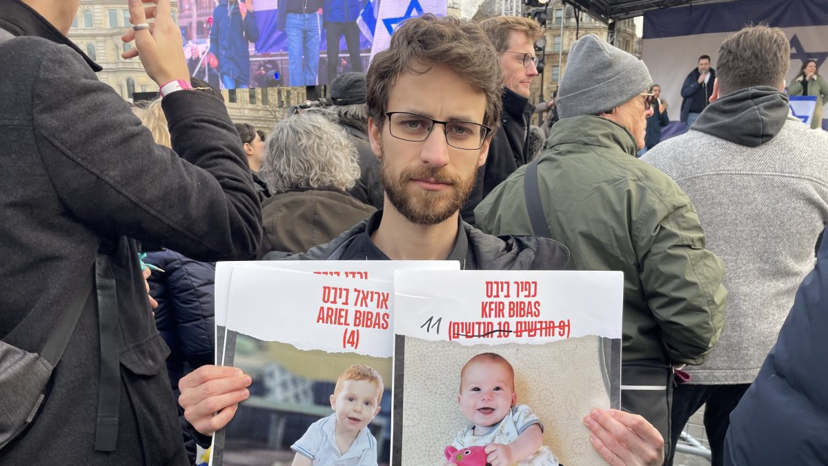 Eylon Keshet holding a photo of his cousin's children, Ariel and Kfir Bibas.