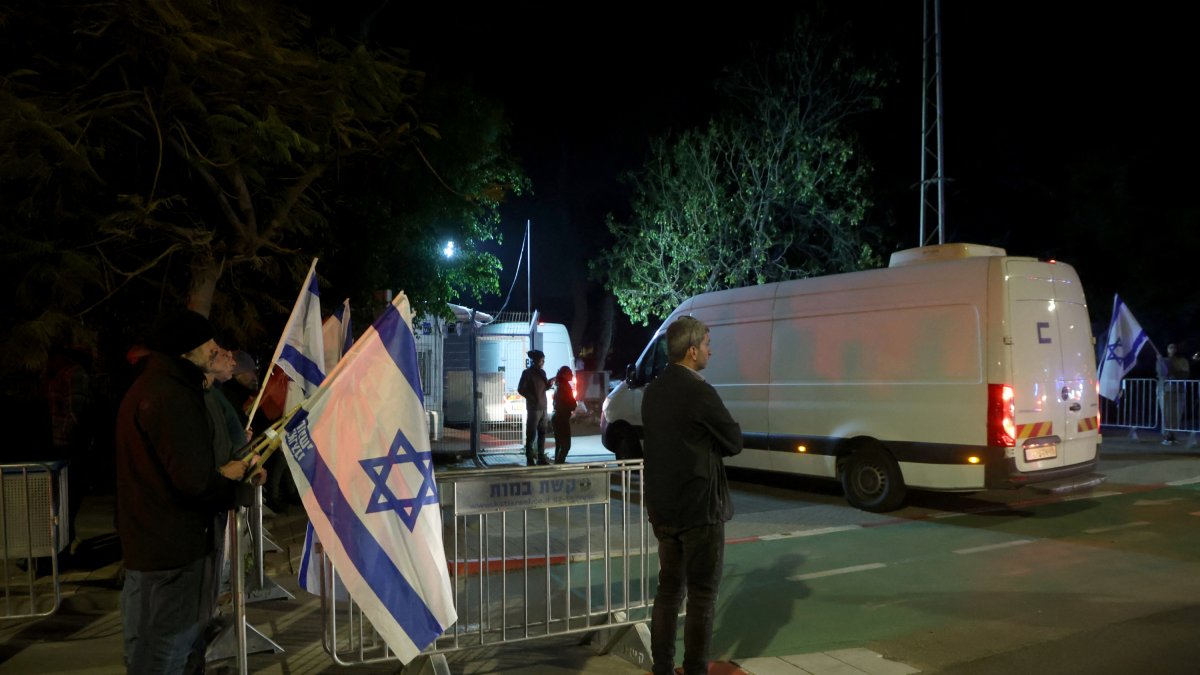 Israelis watch as vans enter a forensic center carrying bodies transferred from Hamas via the Red Cross to Israel