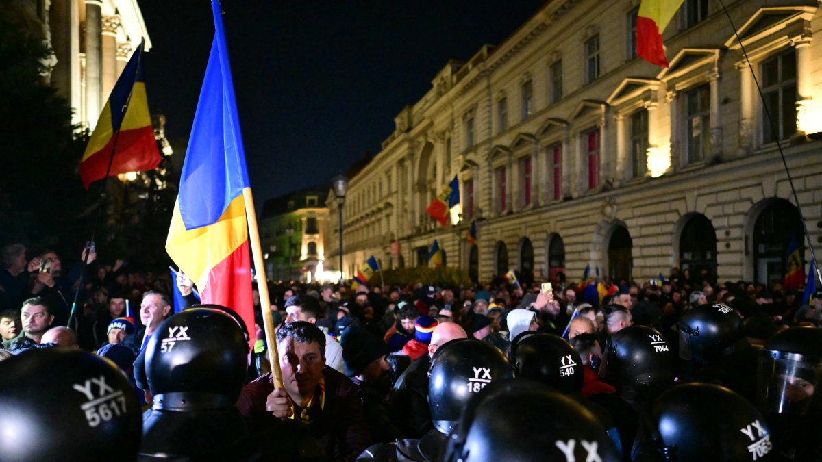 Un partidario del candidato presidencial Călin Georgescu sostiene la bandera rumana.