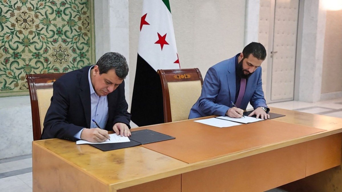 Syria's interim president Ahmed al-Sharaa (R) and Syrian Democratic Forces (SDF) commander-in-chief Mazloum Abdi signing an agreement AFP PHOTO / HO / SANA