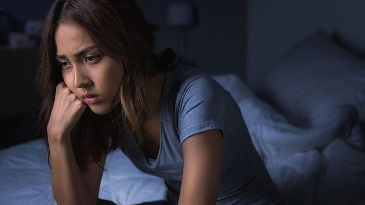 Una mujer sentada al borde de la cama sin lograr conciliar el sueño