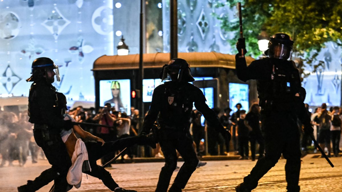 Riot police officers detain a person during celebrations in Paris.