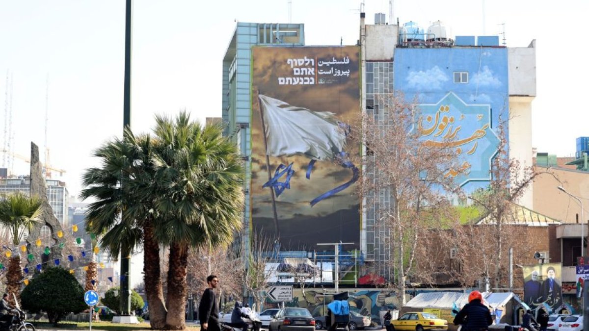 Iraníes pasan junto a un cartel antiisraelí en la Plaza Palestina de Teherán