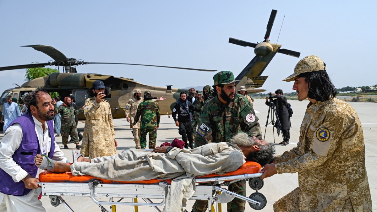 Taliban security personnel carry an earthquake victim.