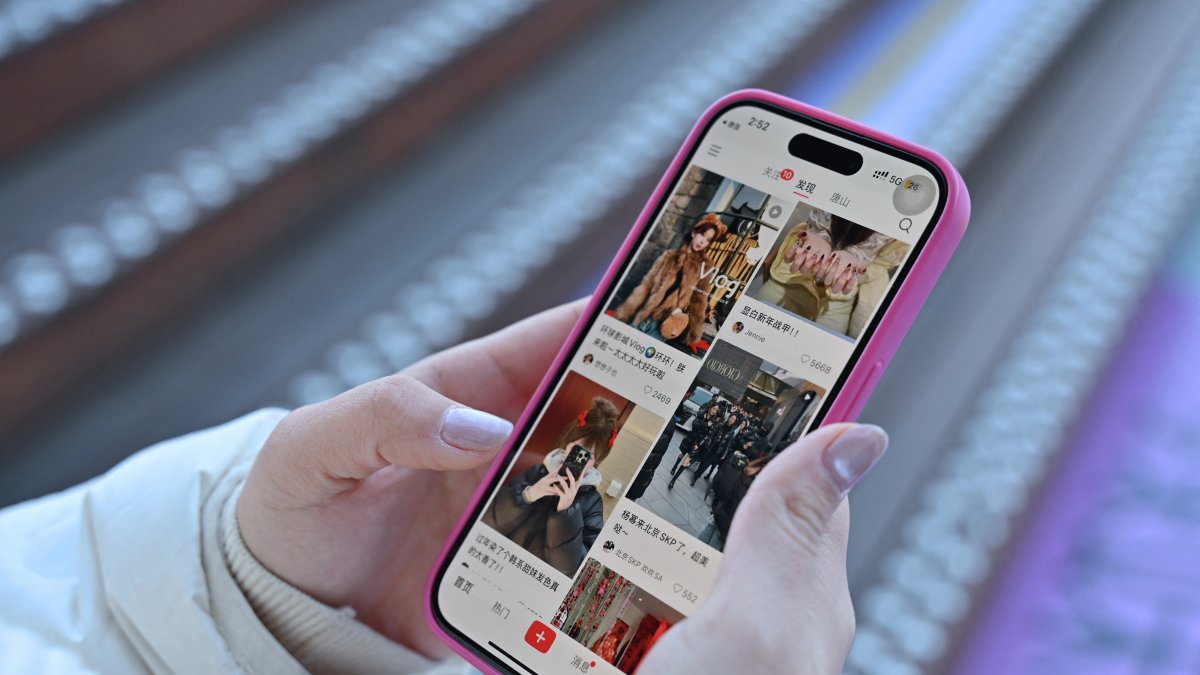 (FILES) A photo of a woman with her phone showing the Chinese app RedNote.