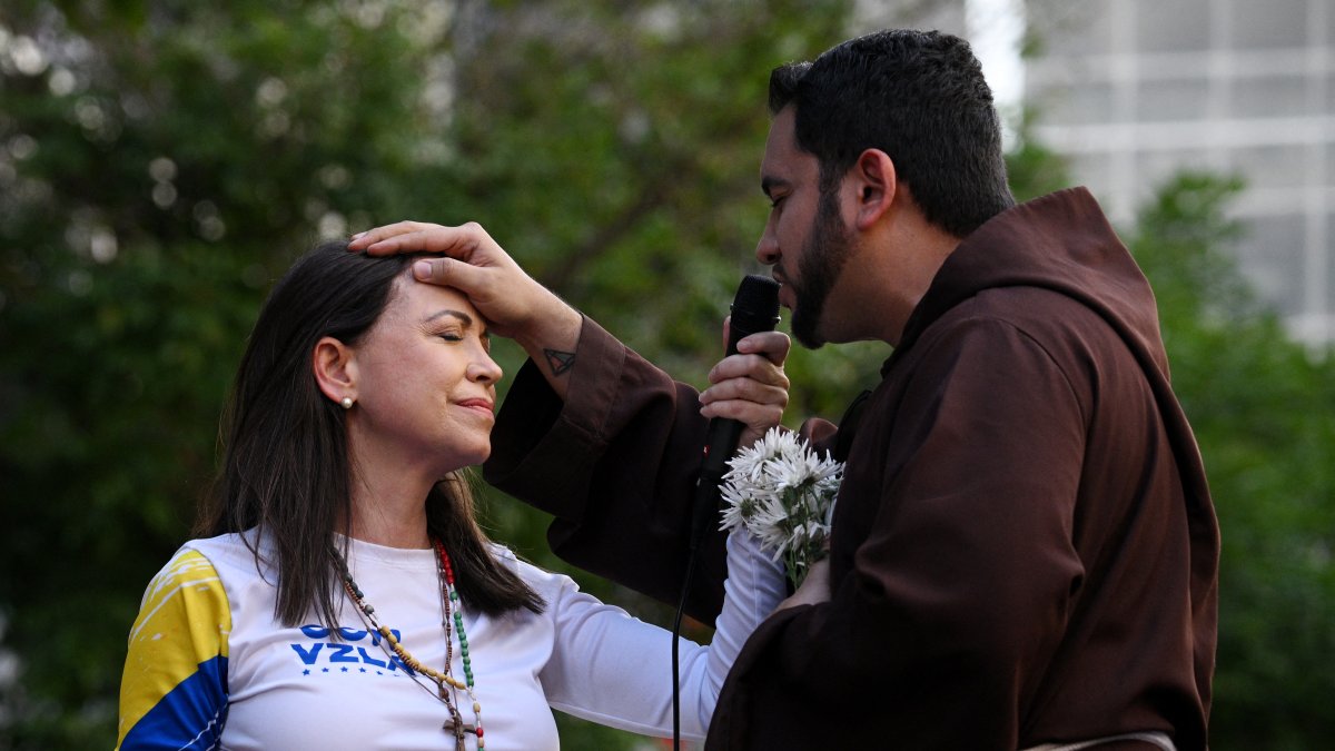 María Corina siendo bendecida por un cura católico durante una protesta en Venezuela.