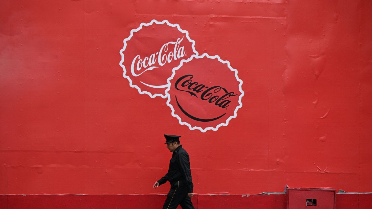 A security guard walks past a Coca-Cola advertisement.