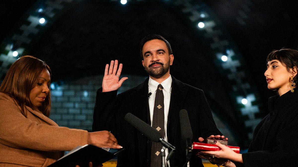 El alcalde electo de Nueva York, Zohran Mamdani (C), coloca su mano sobre un Corán.