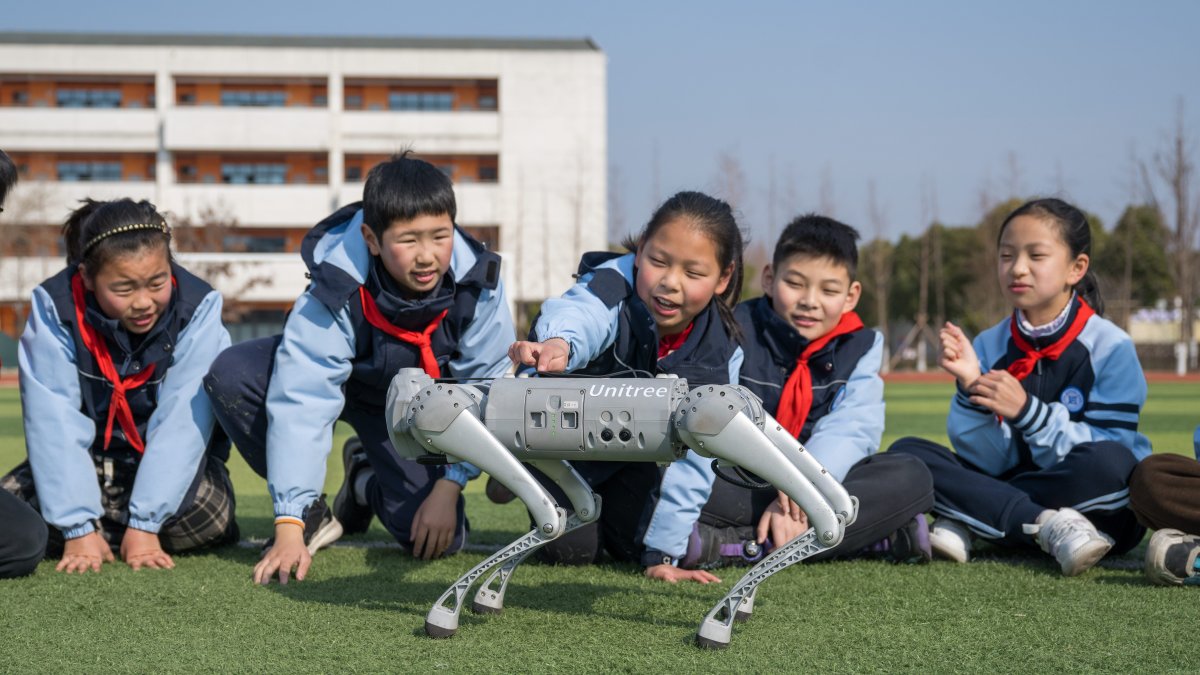 Los alumnos interactúan con un perro robot durante un descanso en clase en la escuela primaria Xinyi.