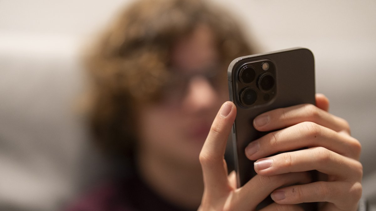 A teenager accesses social networks via his cell phone.