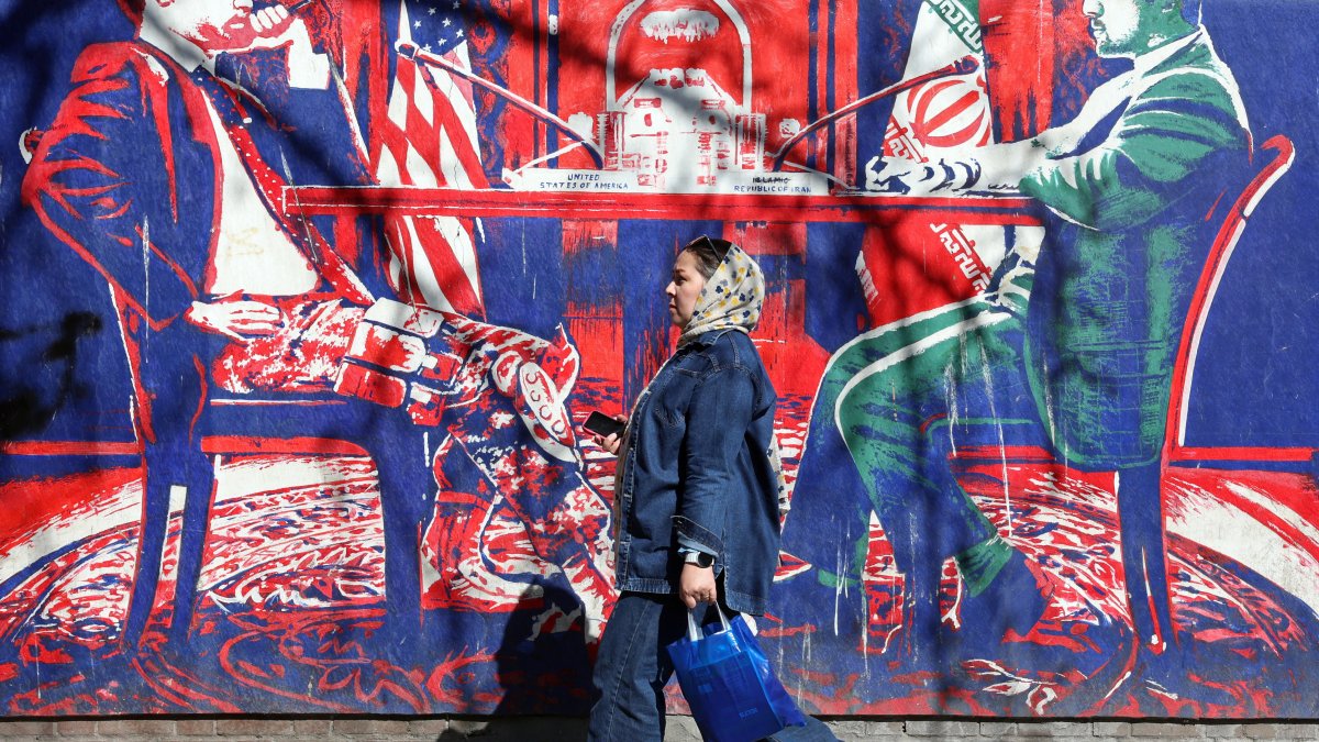 Una mujer iraní pasa junto a un mural que sataniza las conversaciones entre Irán y EEUU