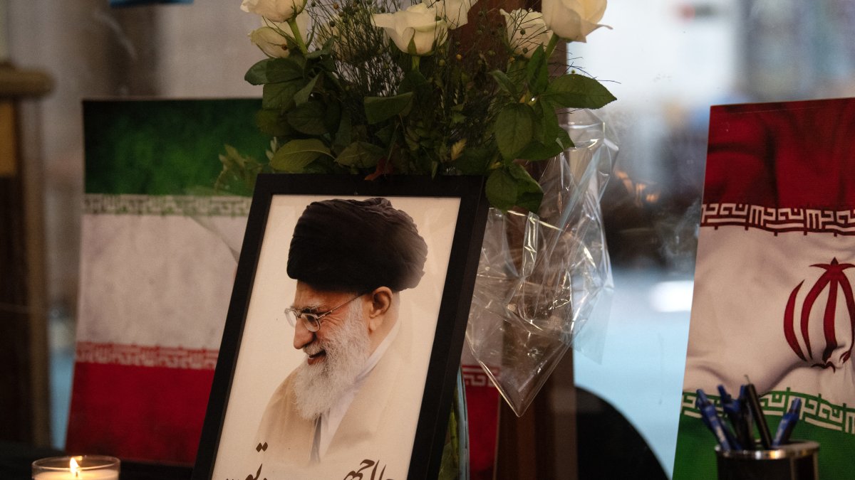 Un retrato de Jamenei junto a un libro de condolencias y velas