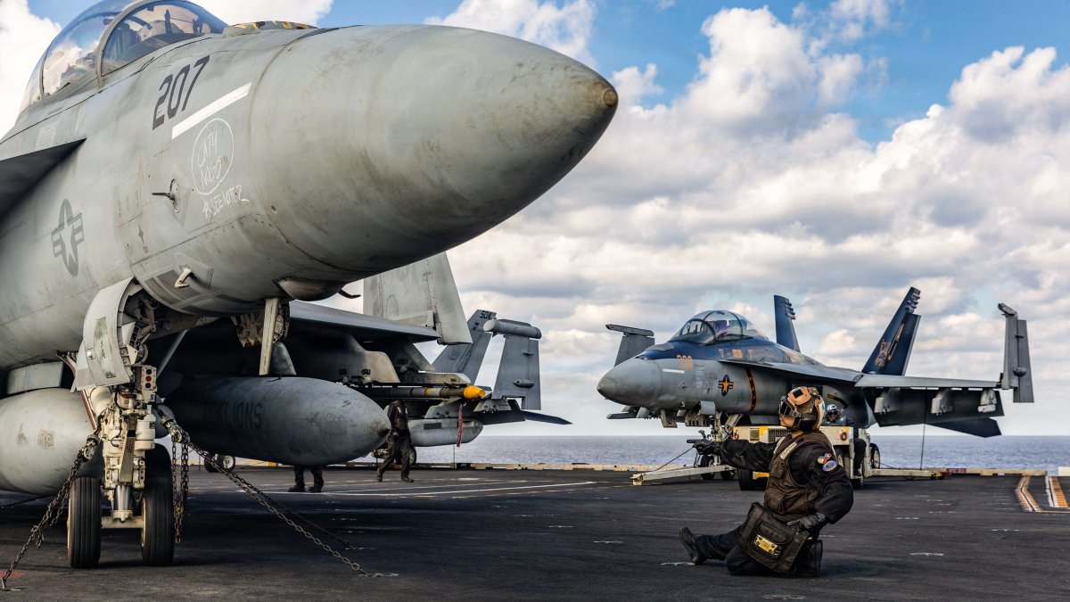 A U.S. Sailor signals to an F/A-18F Super Hornet aircraft