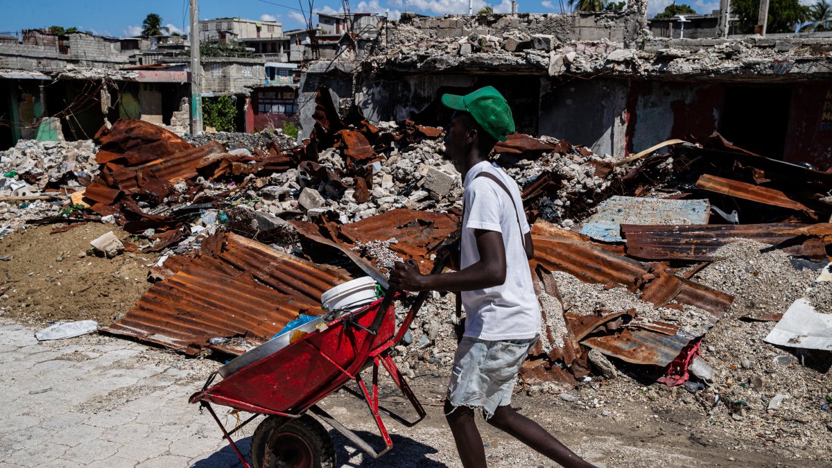 A shopkeeper walks around houses destroyed by armed gangs in a Haitian neighborhood.