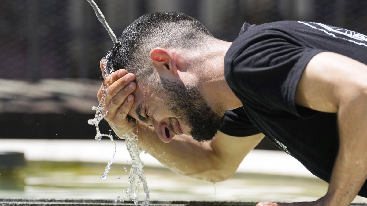 A young boy cools off in a fountain from the high temperatures.