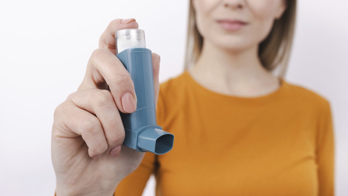 Mujer sosteniendo un inhalador para el asma.