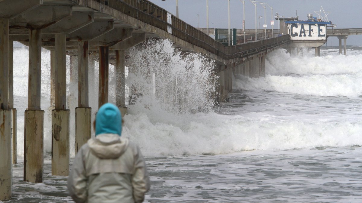 A woman watches as large waves break on the beach (File).