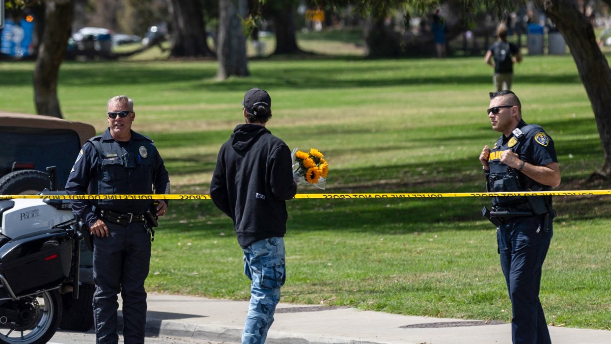 Un hombre lleva flores mientras agentes de la policía de San Diego bloquean el acceso