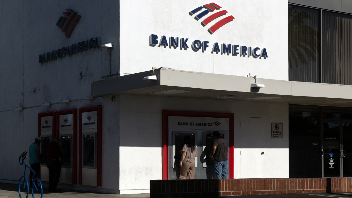 People use ATMs at a Bank of America branch.